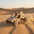 UGEARS Desert Buggy træbyggesæt kører over ørkenklitter i gyldent aftenlys